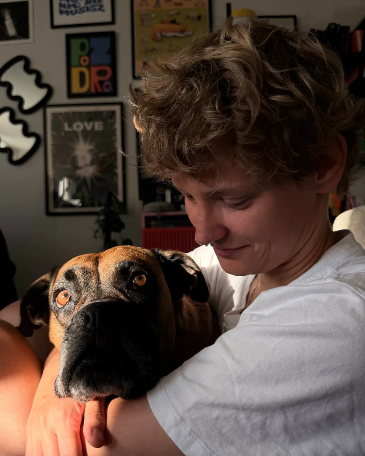 Ola with her arm around a dog that rests its muzzle on her shoulder and looks at the camera